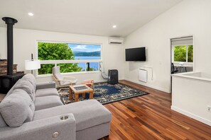 Ein modernes Wohnzimmer mit einer Couch, einem Sessel, einem kleinen Tisch und Blick auf einen See.