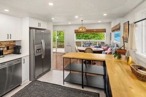 Eine moderne Küche mit integriertem Kühlschrank, einer Kaffeemaschine und einem Essbereich mit Holztisch und Stühlen.