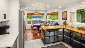 Una cocina moderna con comedor, piso de madera y vistas a zonas verdes.