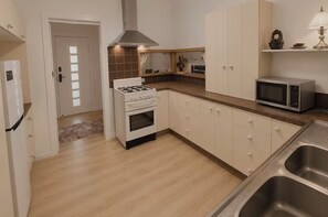 Une cuisine moderne équipée d’une cuisinière, d’un four, d’un four à micro-ondes et d’un évier en acier inoxydable.