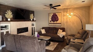 A modern living room with a sofa, armchair, and a fireplace.