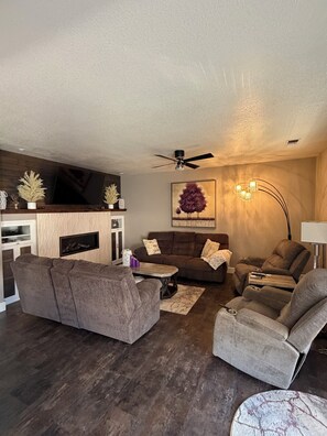 A modern living room with a sofa, armchair, and a fireplace.