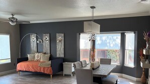 A spacious room with a bed, a dining table, and a chandelier.