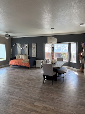 A spacious room with a bed, a dining table, and a chandelier.
