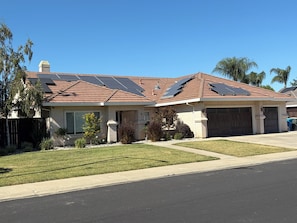Une maison d’habitation avec un toit en pente, des panneaux solaires, un garage et une pelouse bien entretenue.