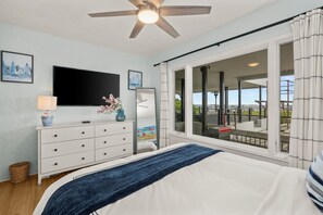 Ein Schlafzimmer mit Bett, Fernseher, Kommode und einem großen Fenster mit Blick.