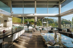 A spacious living area with a large glass table, a sofa set, and a view of the outdoors. - Hollywood Hills Private Oasis with amazing views (Los Angeles)