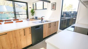 Une cuisine moderne avec des meubles en bois, un lave-vaisselle, un évier et un coin repas avec des chaises.