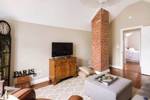 Ein Wohnzimmer mit Fernseher, Holzschrank und Kamin aus Backsteinen.