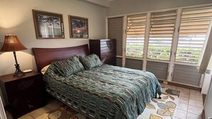 A bedroom with a bed, nightstands, a ceiling fan, and a window with blinds.
