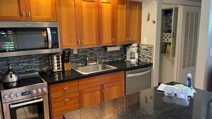 A kitchen with wooden cabinets, a stainless steel microwave, an oven, a coffee maker, and a dishwasher.