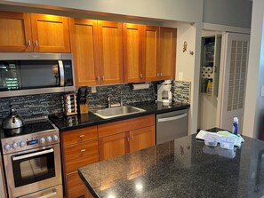 Eine Küche mit Holzausstattung, einer Edelstahl-Mikrowelle, einem Backofen, einer Kaffeemaschine und einem Geschirrspüler.