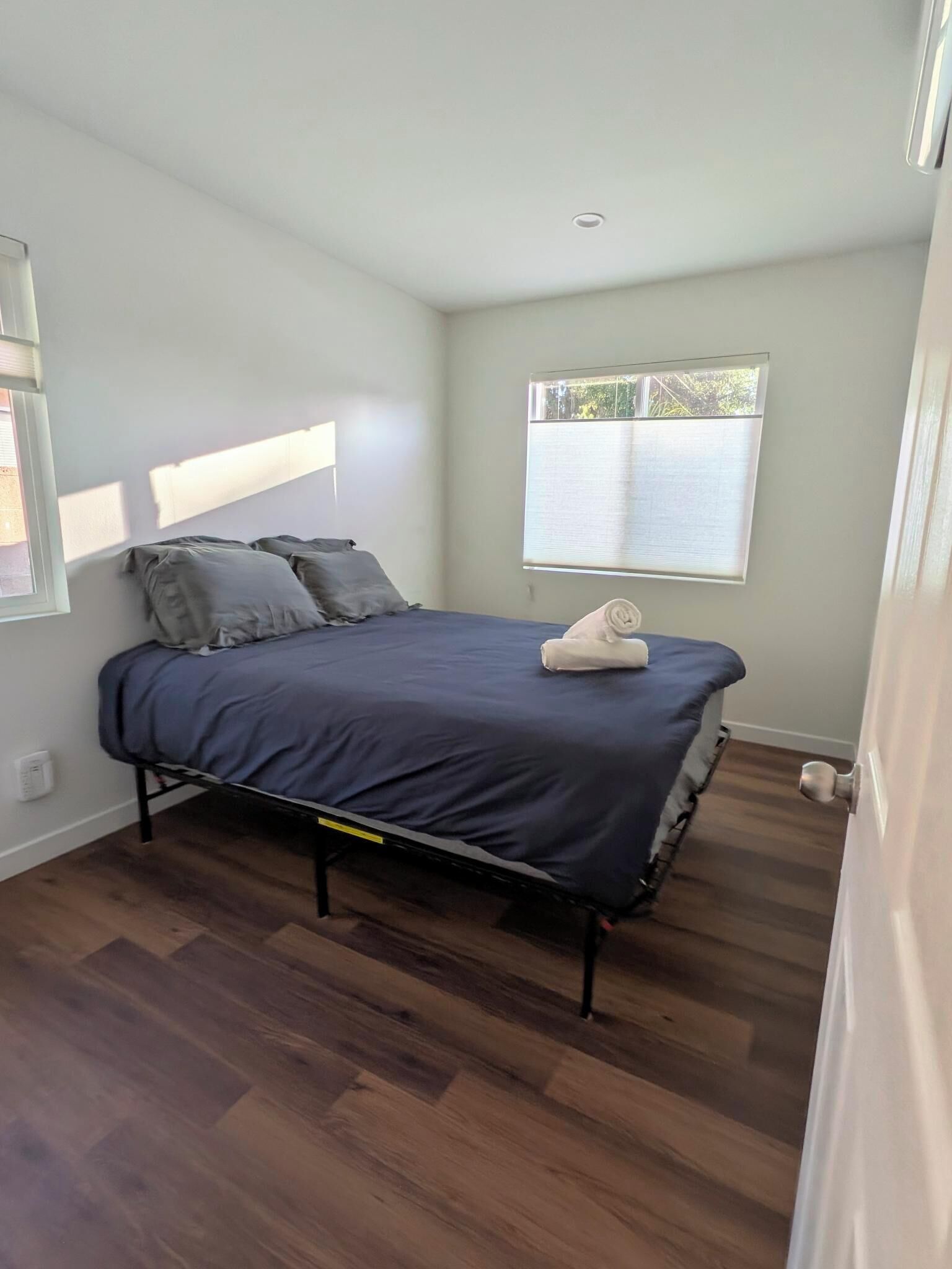 A bedroom with a bed, a window, and a door.