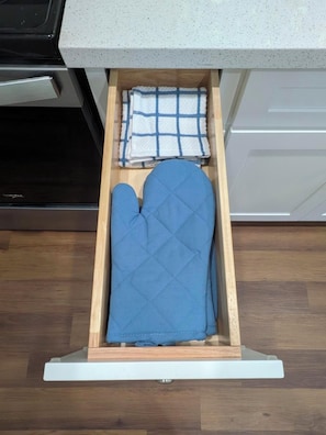 Eine Küchenschublade mit einer blauen Topflappen und einem weißen Handtuch.