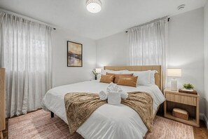 Ein ordentlich eingerichtetes Hotelzimmer mit einem großen Bett, einem Nachttisch mit Lampe und einem gerahmten Bild an der Wand.