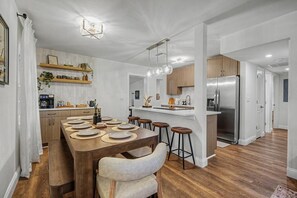 Eine moderne Küche mit Holztisch, Barhocker und Edelstahlgeräten.