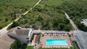 An aerial view of a resort with a swimming pool, lounge chairs, and a beach path. - One Bedroom, Cozy, Beachside, Retreat, with Pool! (Brigantine)