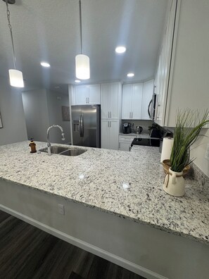 A modern kitchen with granite countertops, stainless steel appliances, and pendant lighting. - Tranquil 3-bedroom house in charming Jacksonville Minutes to San Marco& Downtown (Jacksonville)