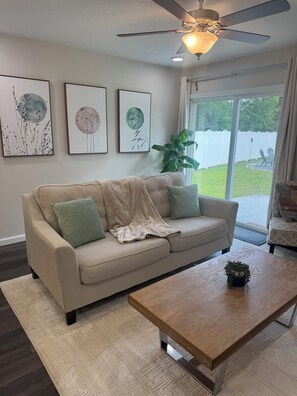 Ein Wohnzimmer mit einem beigefarbenen Sofa, einem Holztisch und drei Wandbildern.