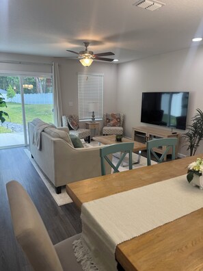 A living room with a sofa, chairs, a coffee table, a TV, and a ceiling fan. - Tranquil 3-bedroom house in charming Jacksonville Minutes to San Marco& Downtown (Jacksonville)