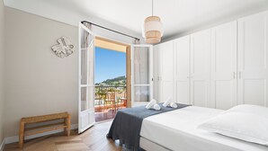 Ein Schlafzimmer mit einem Bett, einer Sitzbank, einer Hängelampe und einer Balkontür.