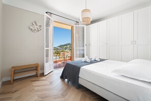 A bedroom with a bed, a bench, a hanging light, and a balcony door. - Le Panoramique Niçois avec Terrasse - Welkeys (Nice)