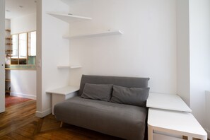 Une pièce moderne avec un canapé gris, des étagères blanches et un plancher en bois.