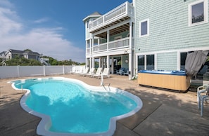 A swimming pool with a curved edge, a hot tub, and a two-story building with a balcony. - Sound Views, Elevator, Pool, Hot Tub, Pets OK, Flex Stays! (Duck)