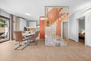 A modern kitchen with white cabinets, a dining area with a white table and brown chairs, and a staircase with a rope barrier. - Villa Kaiserwald by Istrabook (Pula)