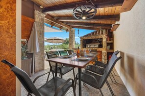 A patio with a table set for dining, outdoor seating, and a stone fireplace. - Villa Kaiserwald by Istrabook (Pula)
