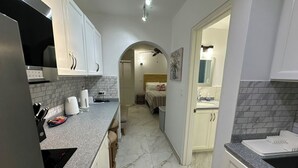 Una cocina con armarios blancos, encimera de granito y salpicadero azulejado.