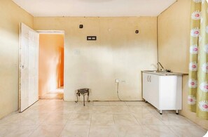 Una habitació amb un armari blanc, una taula petita i una porta que dona a una altra habitació.