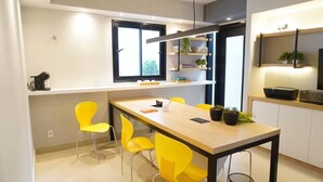 Een moderne keuken met een eettafel, gele stoelen en ingebouwde planken met planten.
