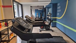 Een sportschool met loopbanden, een muur met motiverende tekst en een zicht op een andere ruimte.