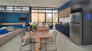 Een moderne keuken met een roestvrijstalen koelkast, een houten eettafel met stoelen, en een groot raam met uitzicht op de stad.