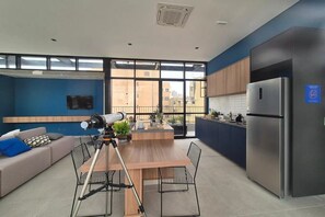 Eine moderne Küche mit einem Edelstahlkühlschrank, einem Holzespeisetisch mit Stühlen und einem großen Fenster mit Blick auf die Stadt.