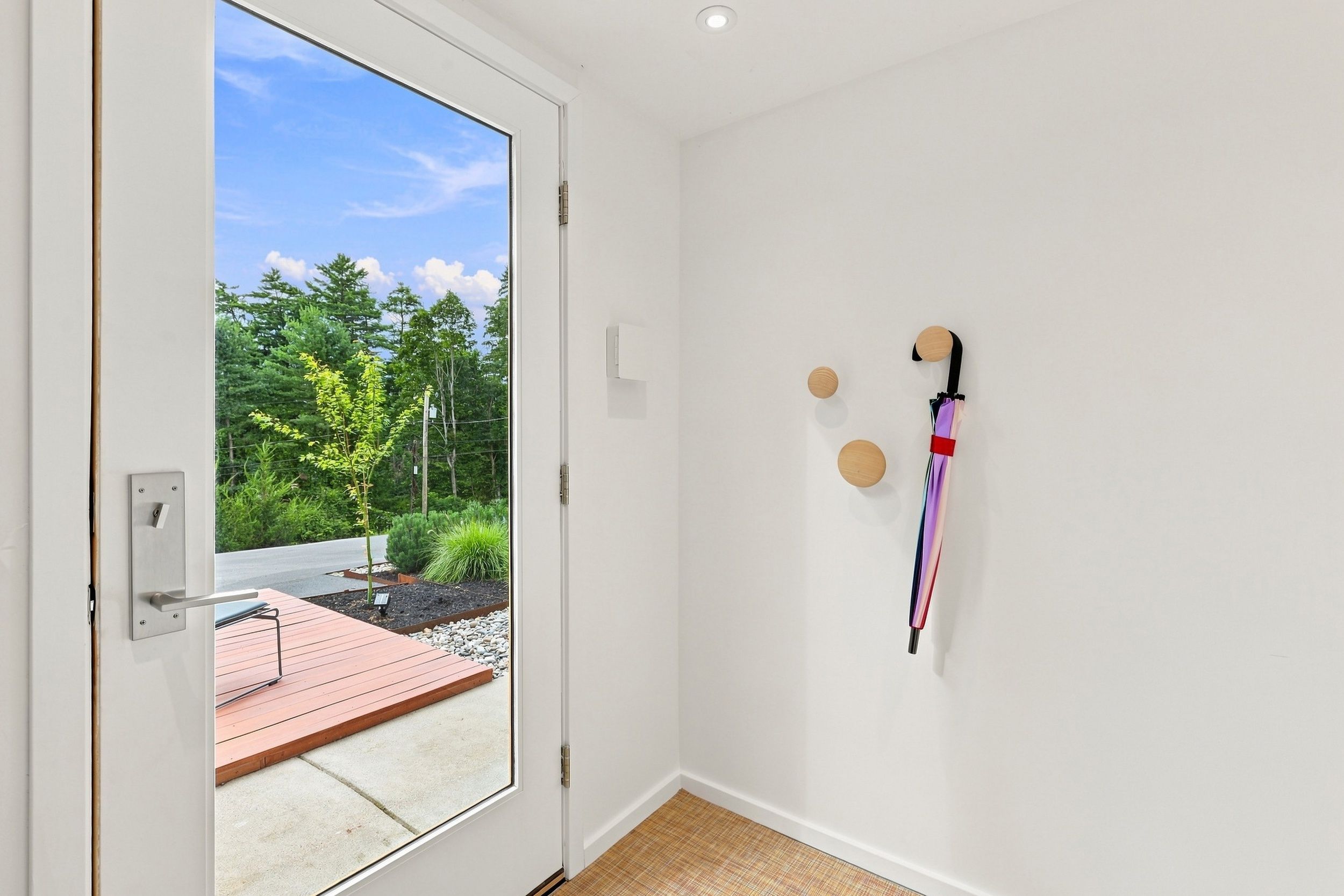 Une pièce dotée d’une porte-fenêtre coulissante donnant sur un espace extérieur avec une terrasse en bois et de la verdure.