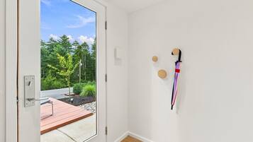 Une pièce dotée d’une porte-fenêtre coulissante donnant sur un espace extérieur avec une terrasse en bois et de la verdure.