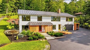 A modern two-story house with a garage, surrounded by a landscaped garden.