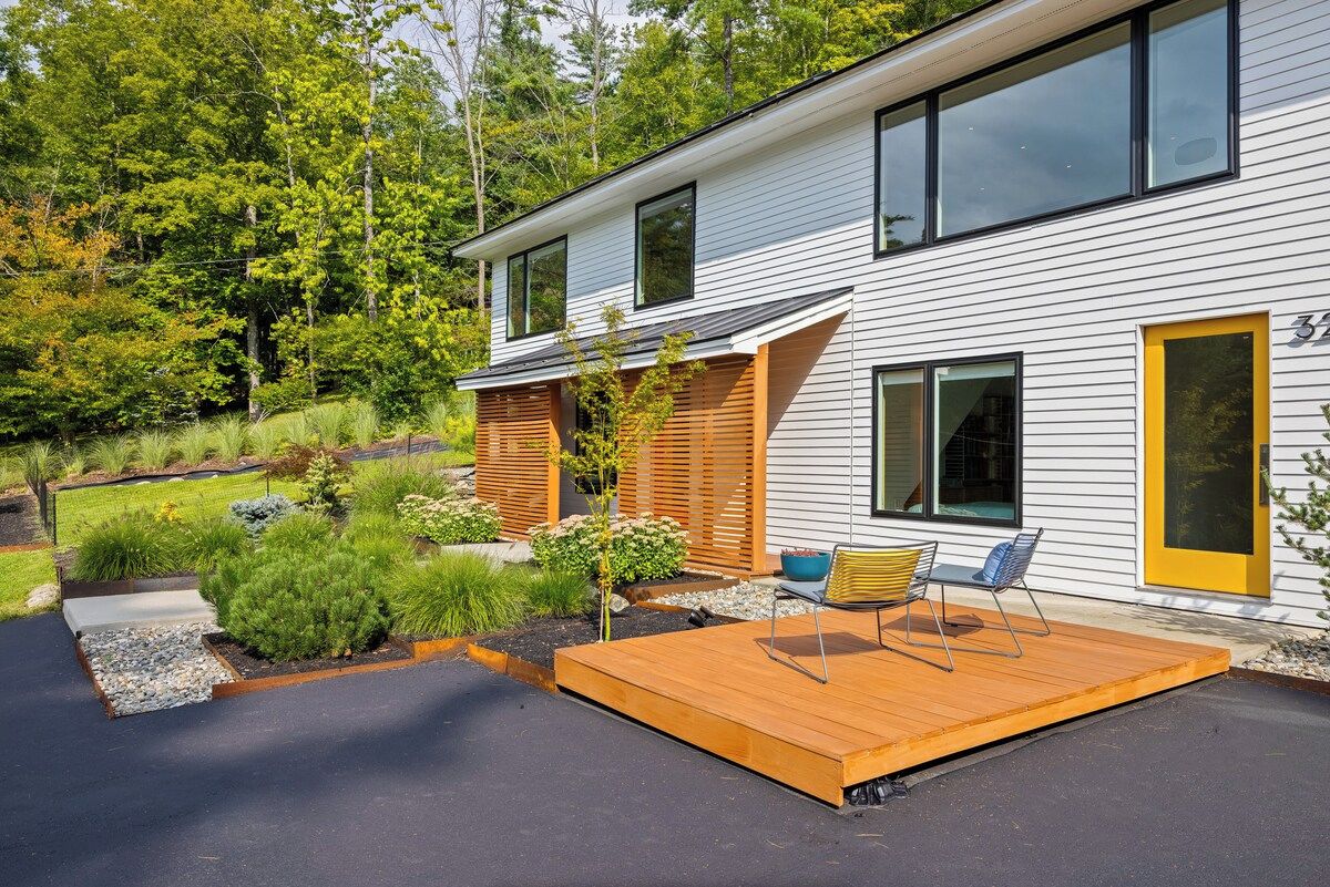 Een modern huis met twee verdiepingen, een terras en een aangelegde tuin.