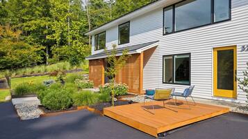 Een modern huis met twee verdiepingen, een terras en een aangelegde tuin.