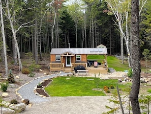 Una cabaña con terraza, rodeada de bosque.