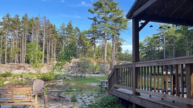 A wooden deck with a stone pathway, a bench, and a picnic table.