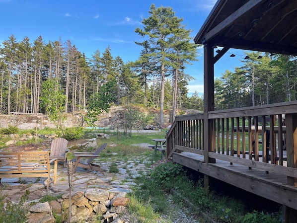 Una terraza de madera con un sendero de piedra, un banco y una mesa de picnic.
