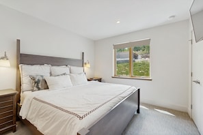 A bedroom with a bed, bedside tables, a window with a view, and a door. - Ski-In/Ski-Out Luxury with Year-Round Resort Amenities (Ludlow)