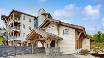 A multi-story building with a covered entrance, balconies, and a stone foundation.