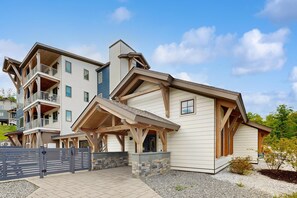 A multi-story building with a covered entrance, balconies, and a stone foundation. - Ski-In/Ski-Out Luxury with Year-Round Resort Amenities (Ludlow)