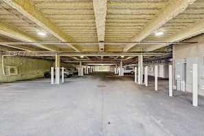A parking garage with concrete floors and white pillars, featuring multiple parking spaces and overhead lighting. - Ski-In/Ski-Out Luxury with Year-Round Resort Amenities (Ludlow)