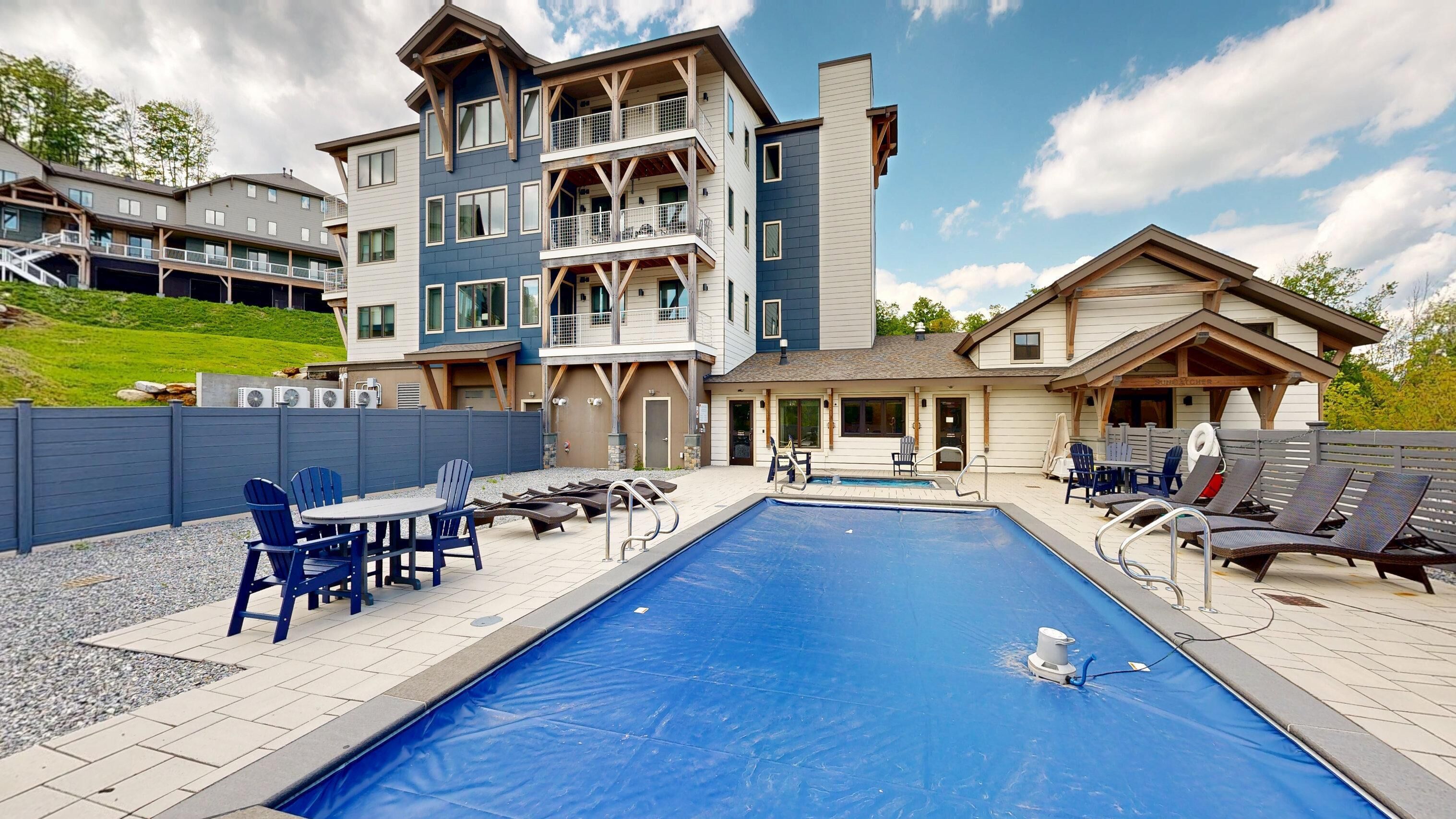 A multi-story building with a pool, outdoor seating, and a covered area.