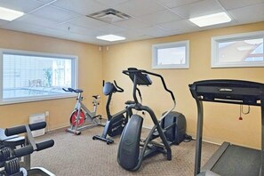 Ein Fitnessstudio mit Trainingsgeräten, großen Fenstern und Blick ins Freie.